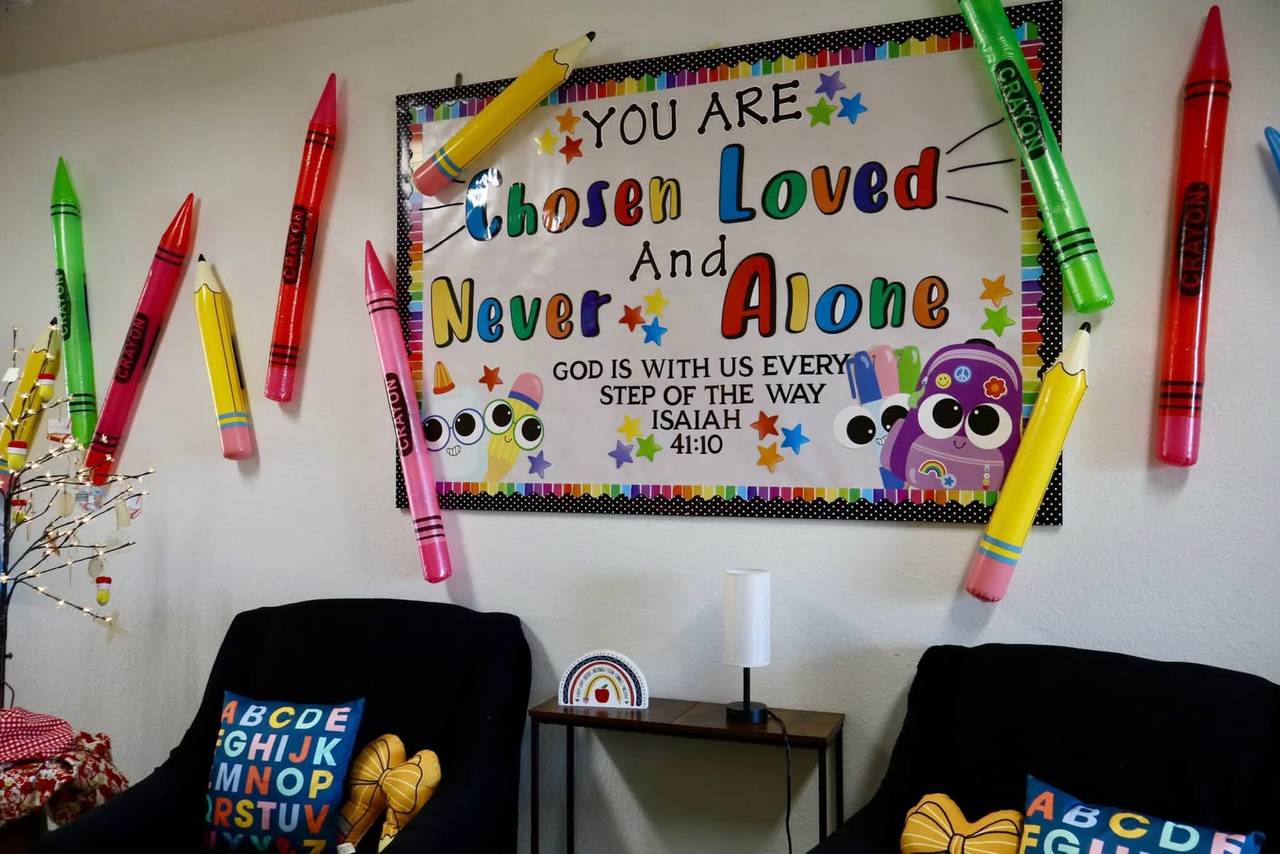 Classroom bulletin board at Stephenville Christian Academy reading 'You Are Chosen, Loved, and Never Alone' with Isaiah 41:10, surrounded by colorful crayon and pencil decor