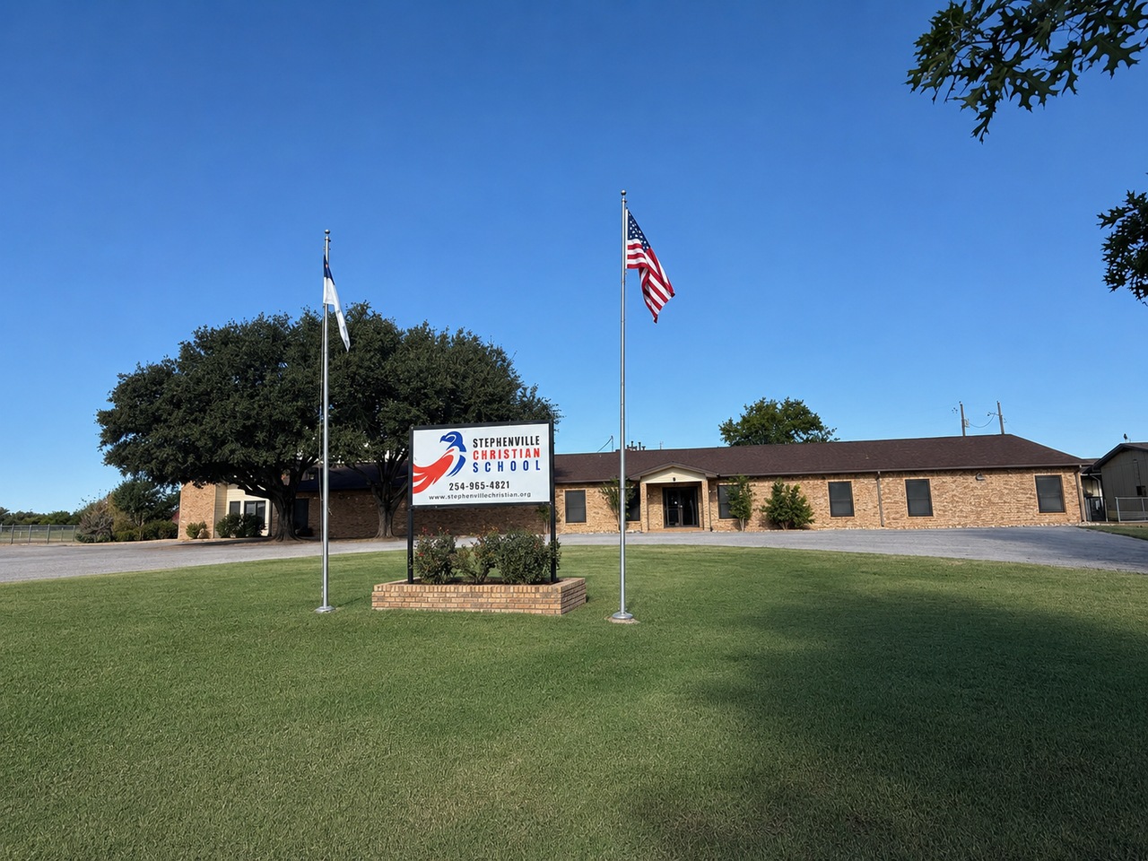 Stephenville Christian Academy campus exterior — front entrance with flagpoles and school sign in Stephenville, TX